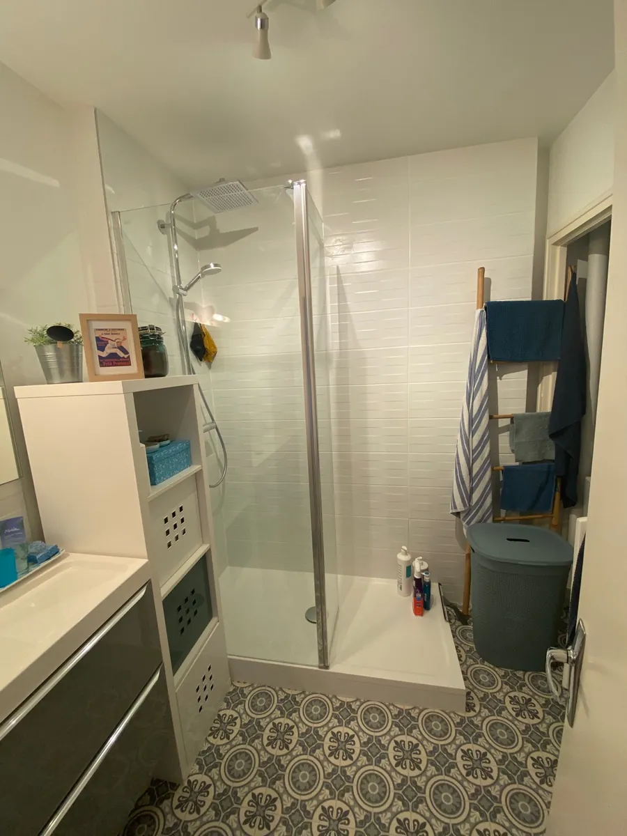 Salle d'eau terminée, douche vitrée, meuble vasque et sol à motifs